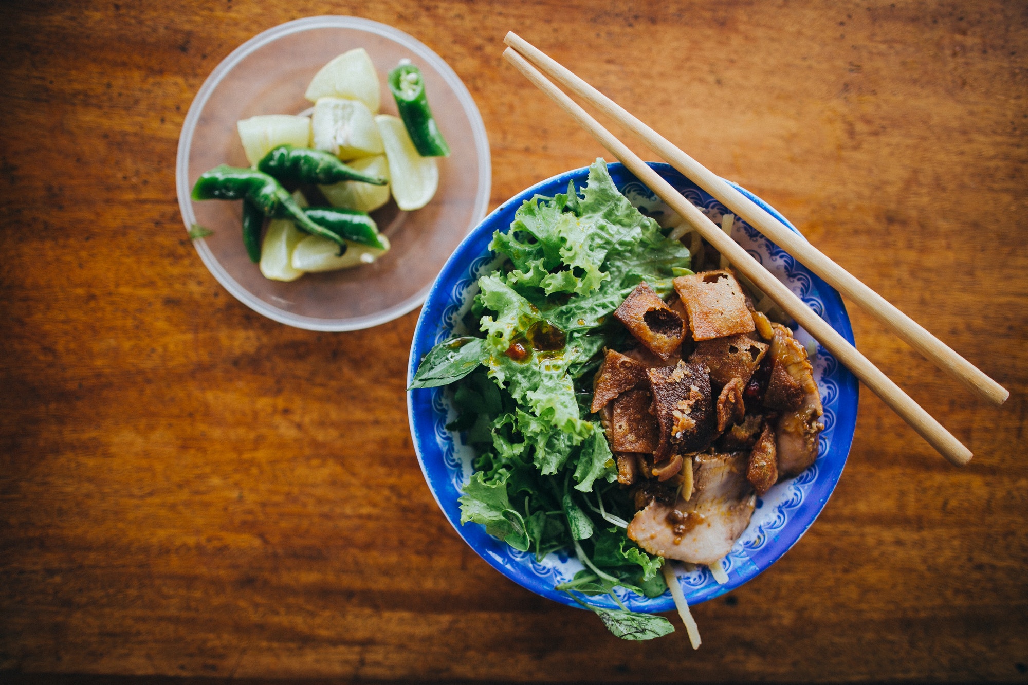 top view of delicious vietnamese food in bowls with chopsticks on wooden table