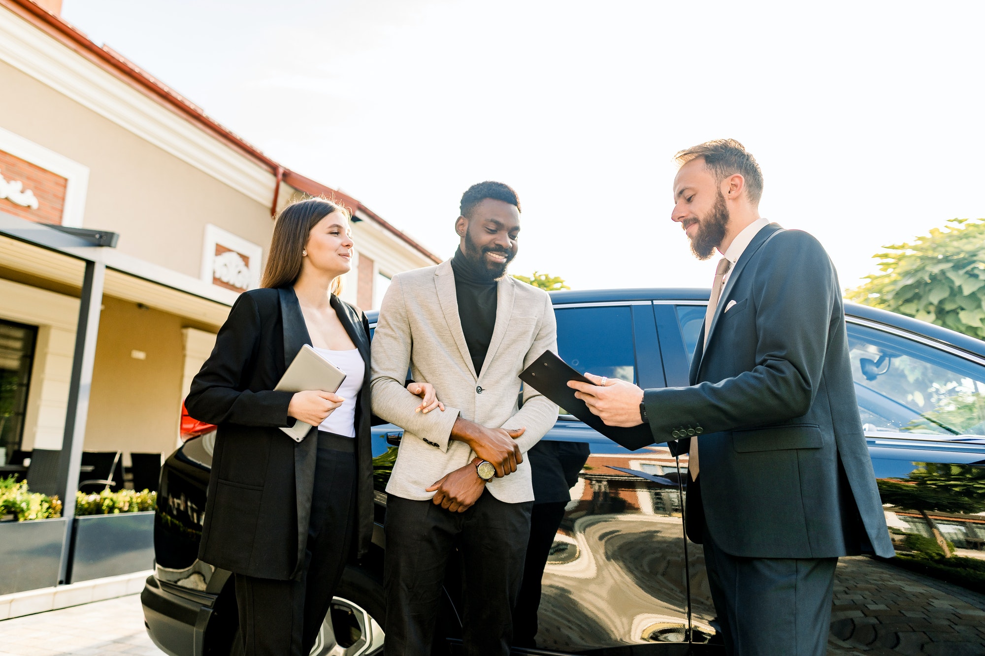 Young People business couple African man and Caucasian woman standing outdoors in a Car Rental